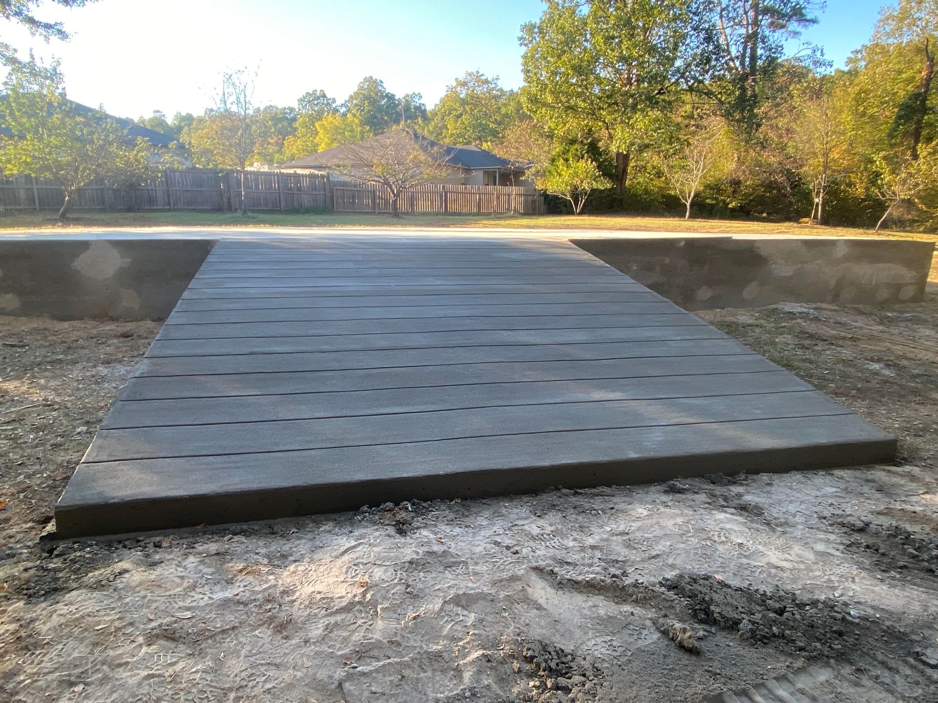 Freshly poured concrete patio next to a building and grass.