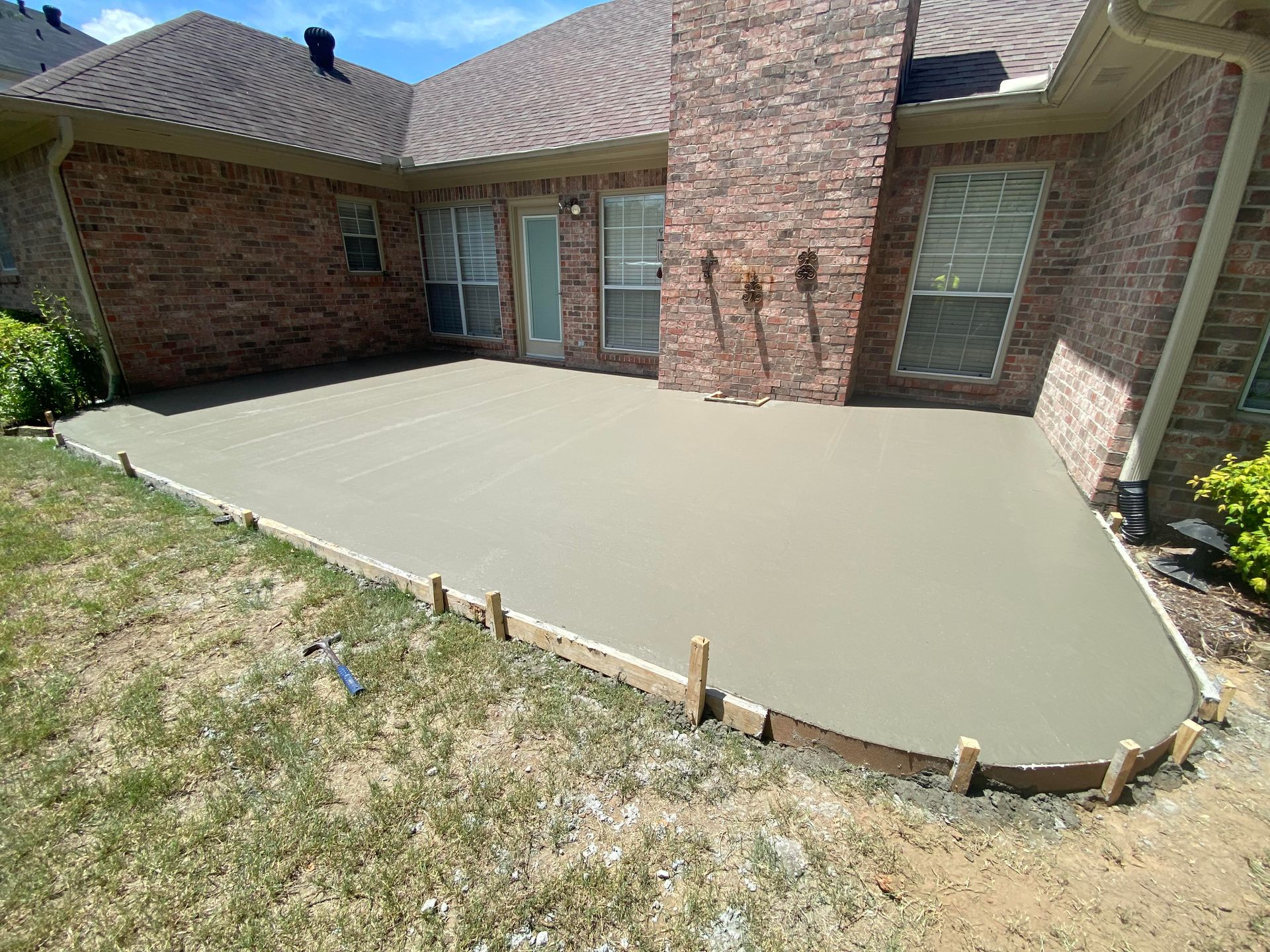 Patio with various-colored stone tiles next to a green lawn.