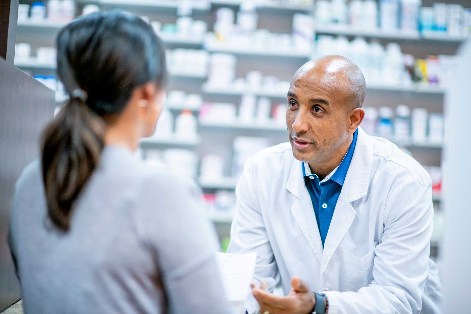 A pharmacist is talking to a patient in a pharmacy.