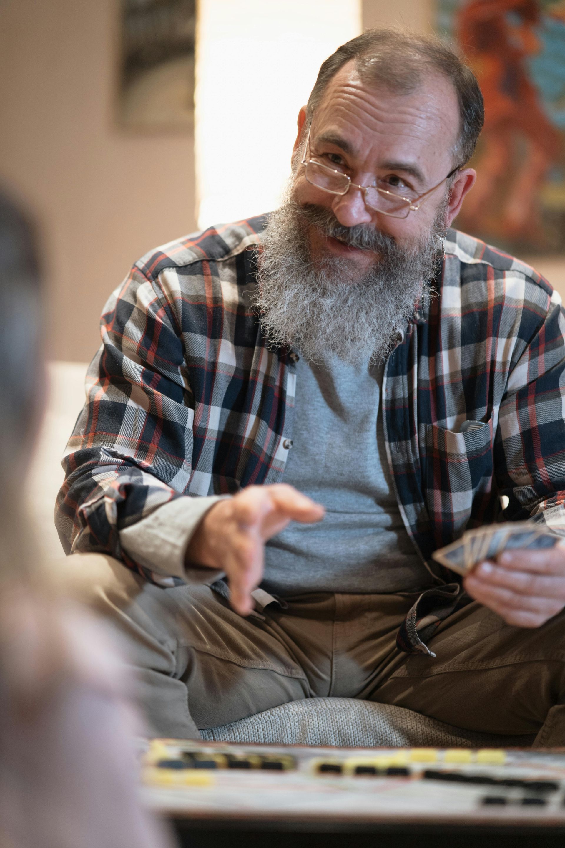 A man with a beard and glasses is playing a game of cards.
