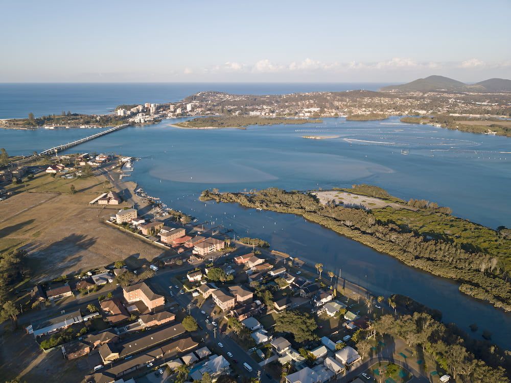 An Aerial View Of A Small Town Next To A Large Body Of Water — Alex's Vegetation in Bonny Hills, NSW