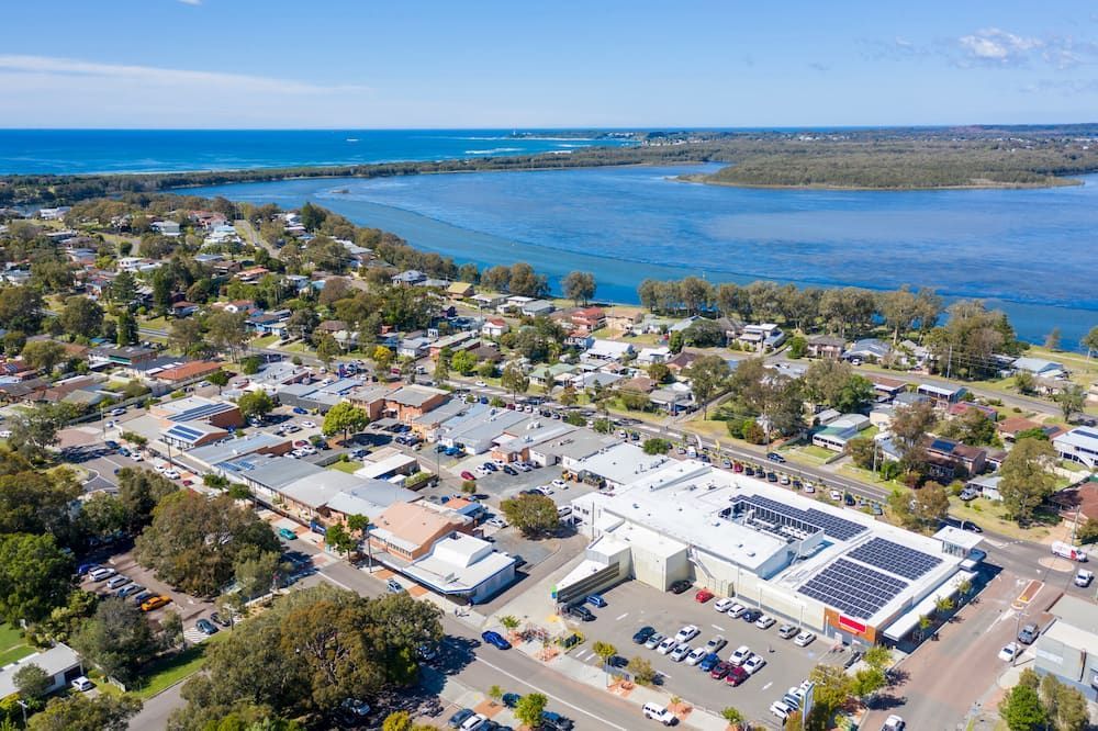 An Aerial View Of A Small Town Next To A Body Of Water — Alex's Vegetation in Bonny Hills, NSW