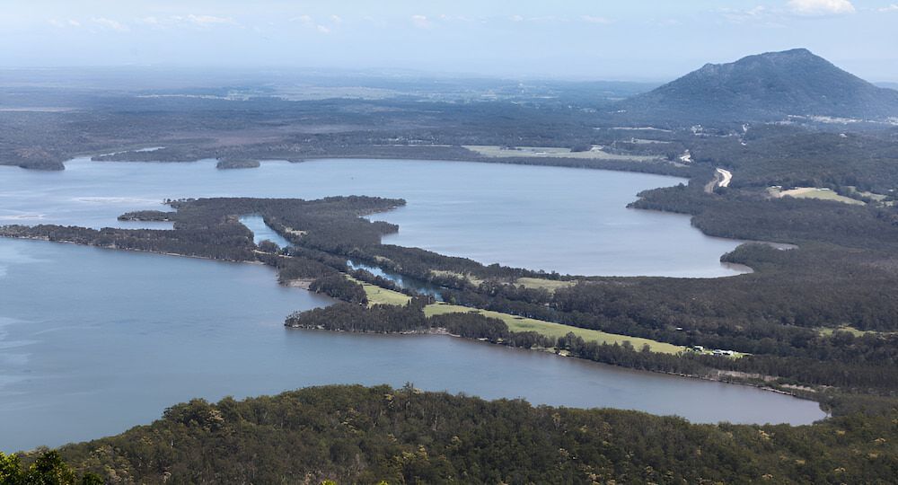 An Aerial View Of A Large Body Of Water Surrounded By Trees And Mountains — Alex's Vegetation in Laurieton, NSW