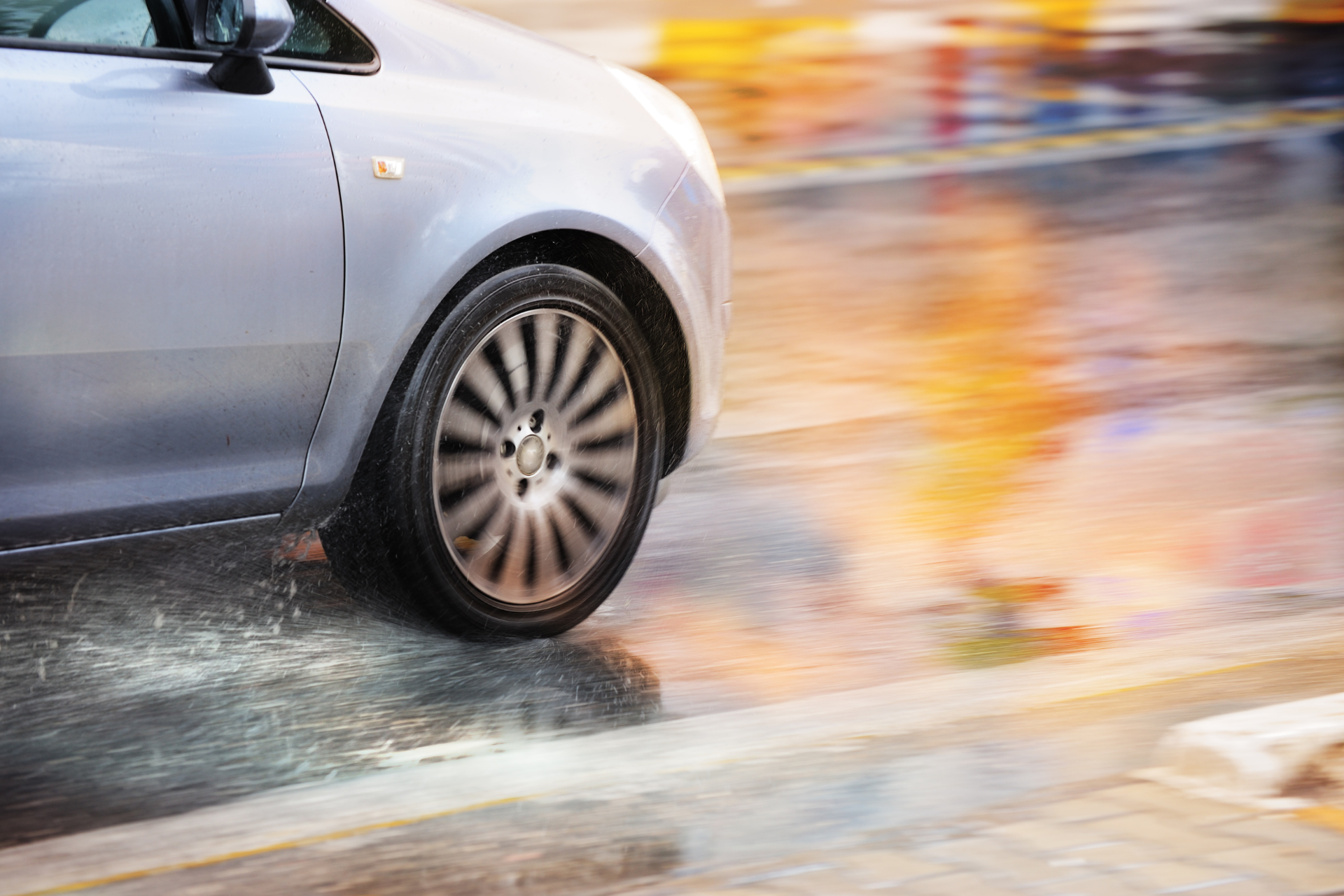 A car is driving down a wet street in the rain.