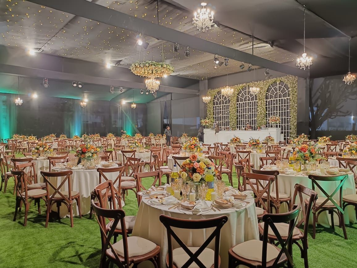 Elegante salón de banquetes decorado con mesas redondas, centros de mesa florales e iluminación 