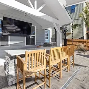 Outdoor patio with bar seating, wall-mounted TV, and white canopy cover