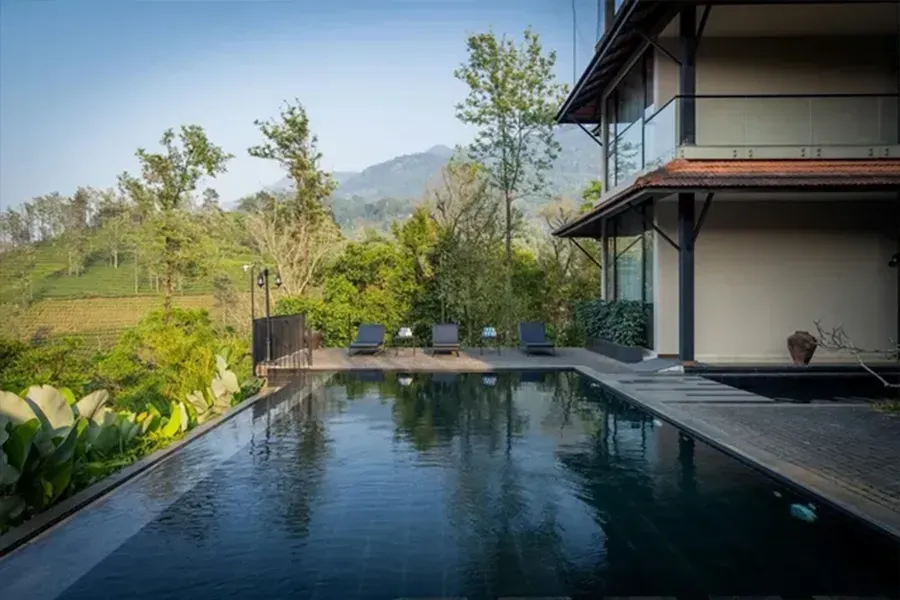 Infinity pool beside a modern villa, overlooking lush hills and mountains