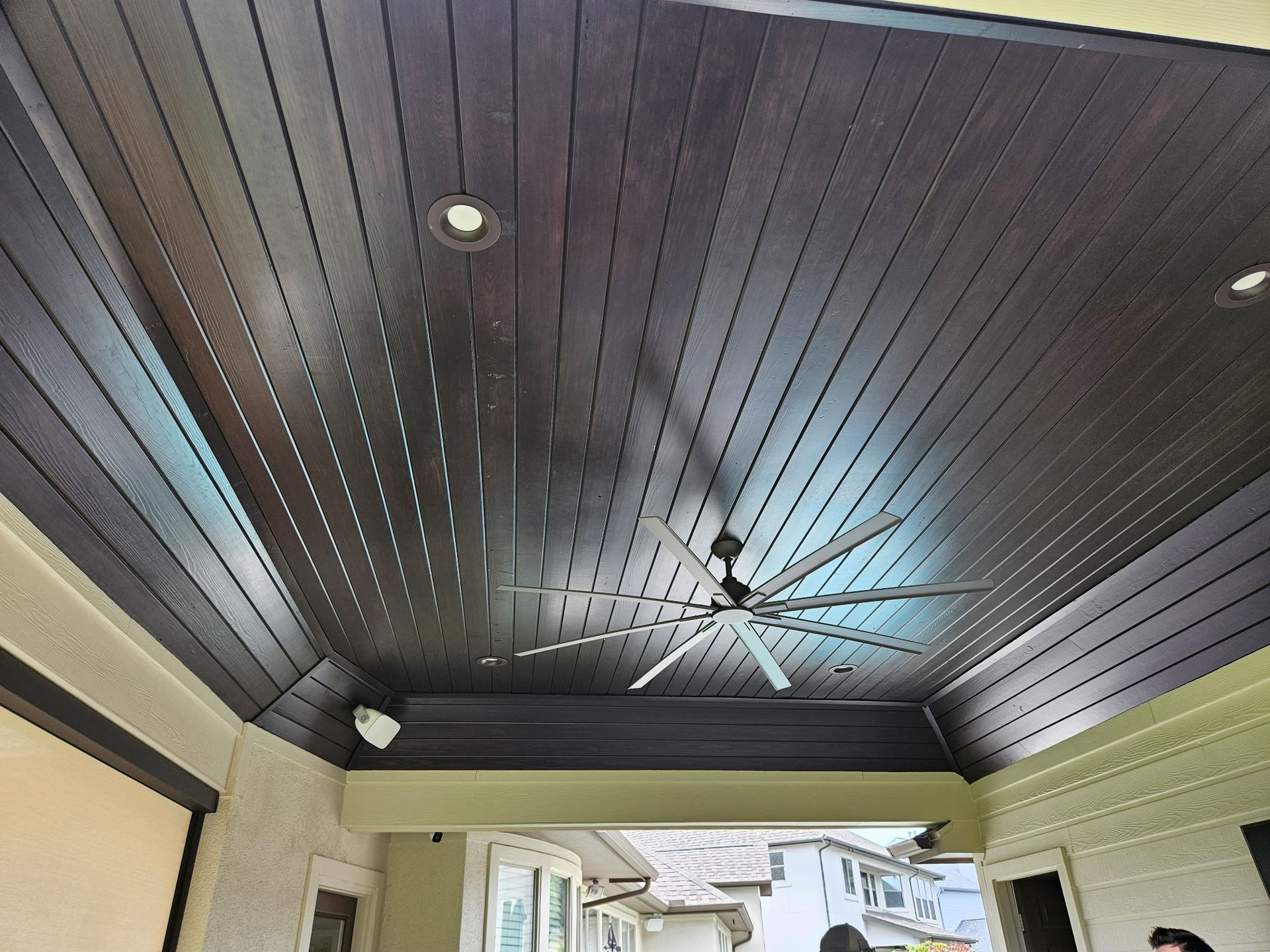 Covered patio ceiling with dark wood planks, a ceiling fan, and recessed lights