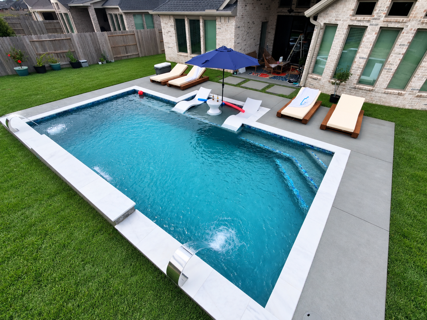 Indoor hot tub beside an open patio with a lit swimming pool at dusk