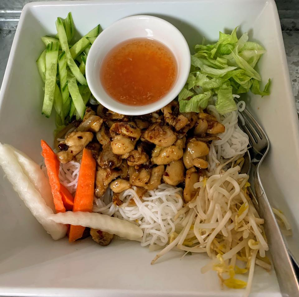 A bowl of food with noodles carrots and sauce
