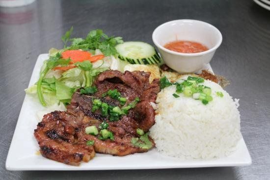 A plate of food with rice , meat and vegetables on a table.
