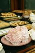 A plate of cupcakes with pink frosting on a table.
