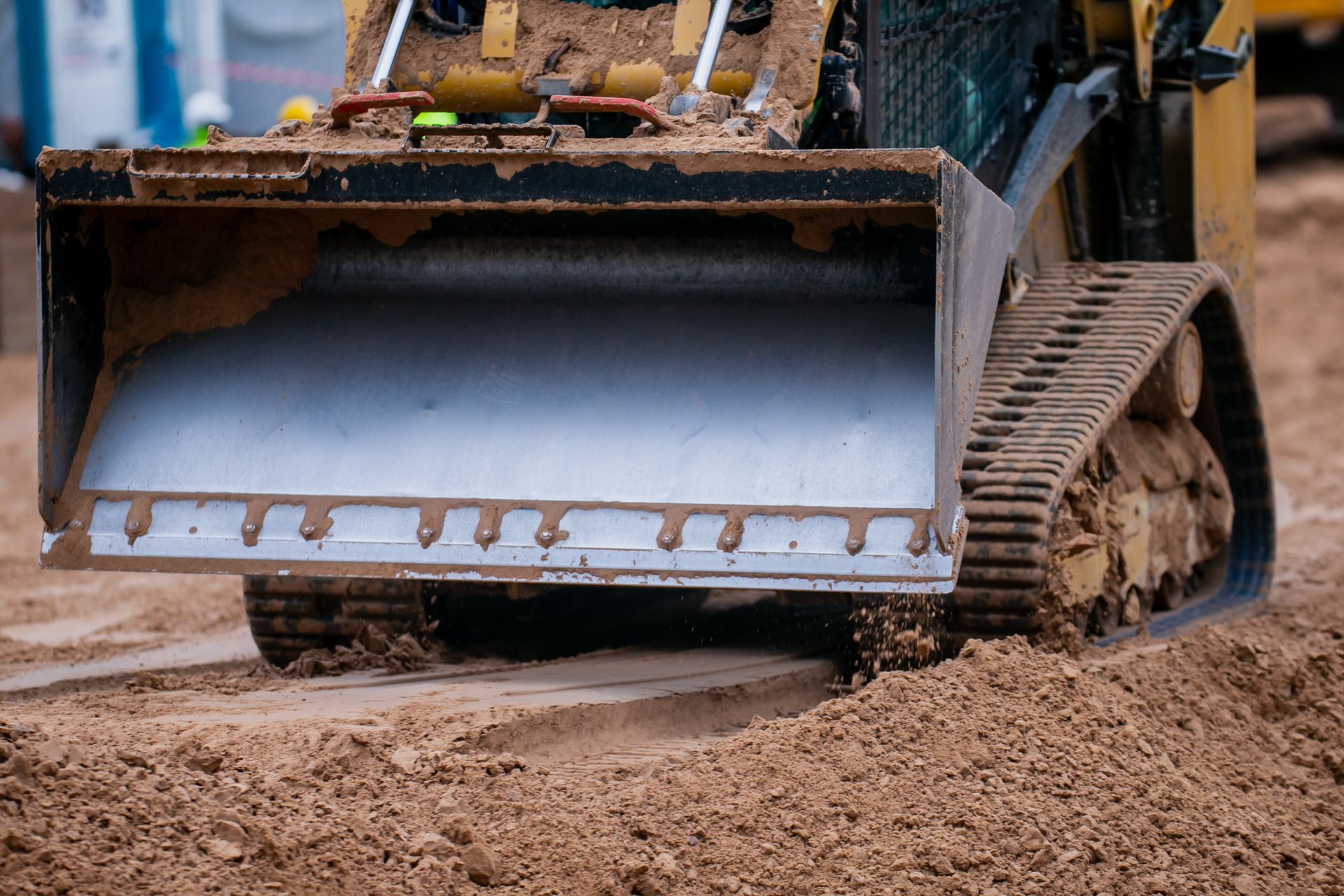 Yellow skid steer with a dirt-filled bucket on a construction site. Yellow skid steer with a dirt-filled bucket on a construction site.