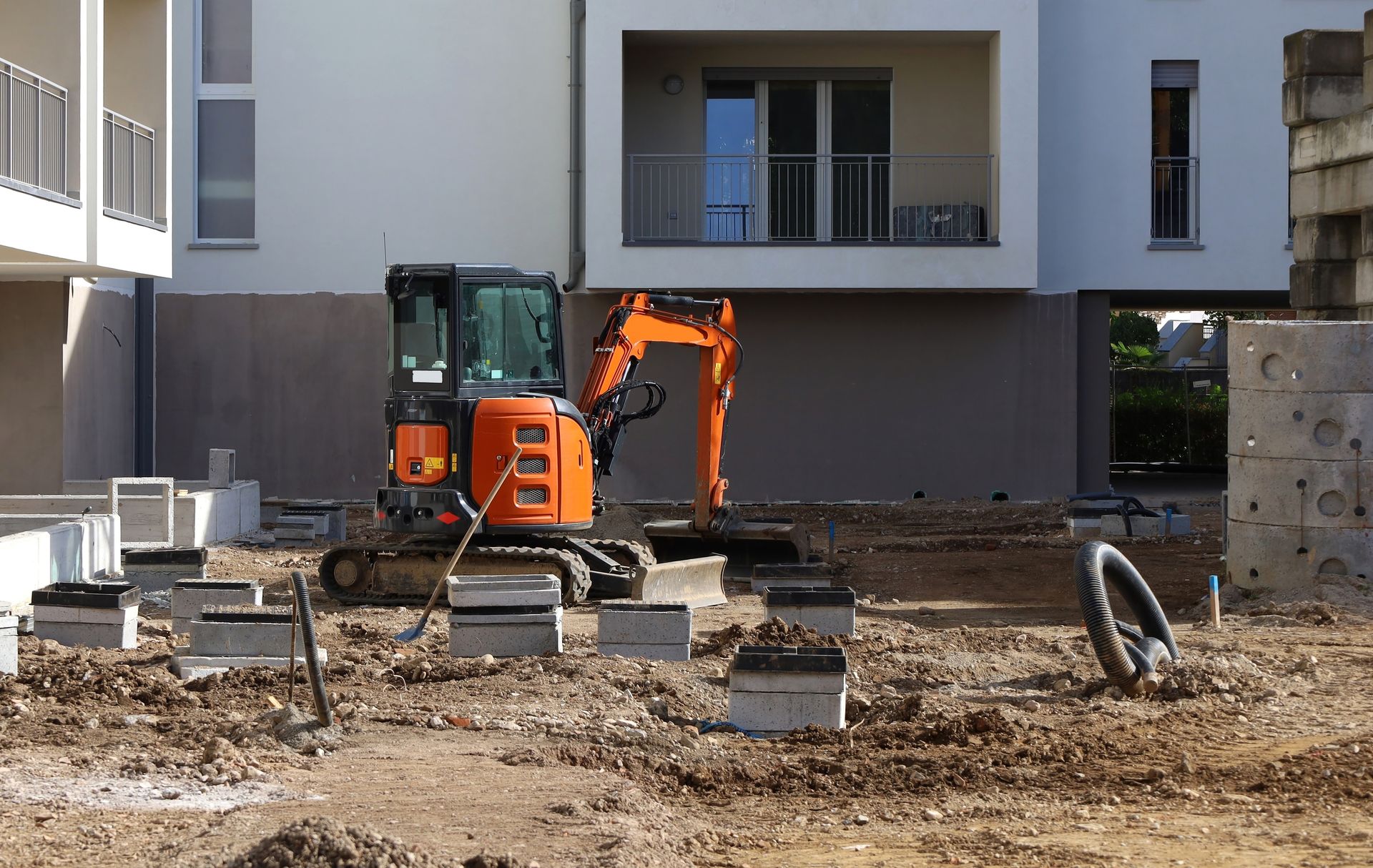 Orange excavator on a construction site with building in the background. Orange excavator on a construction site with building in the background.