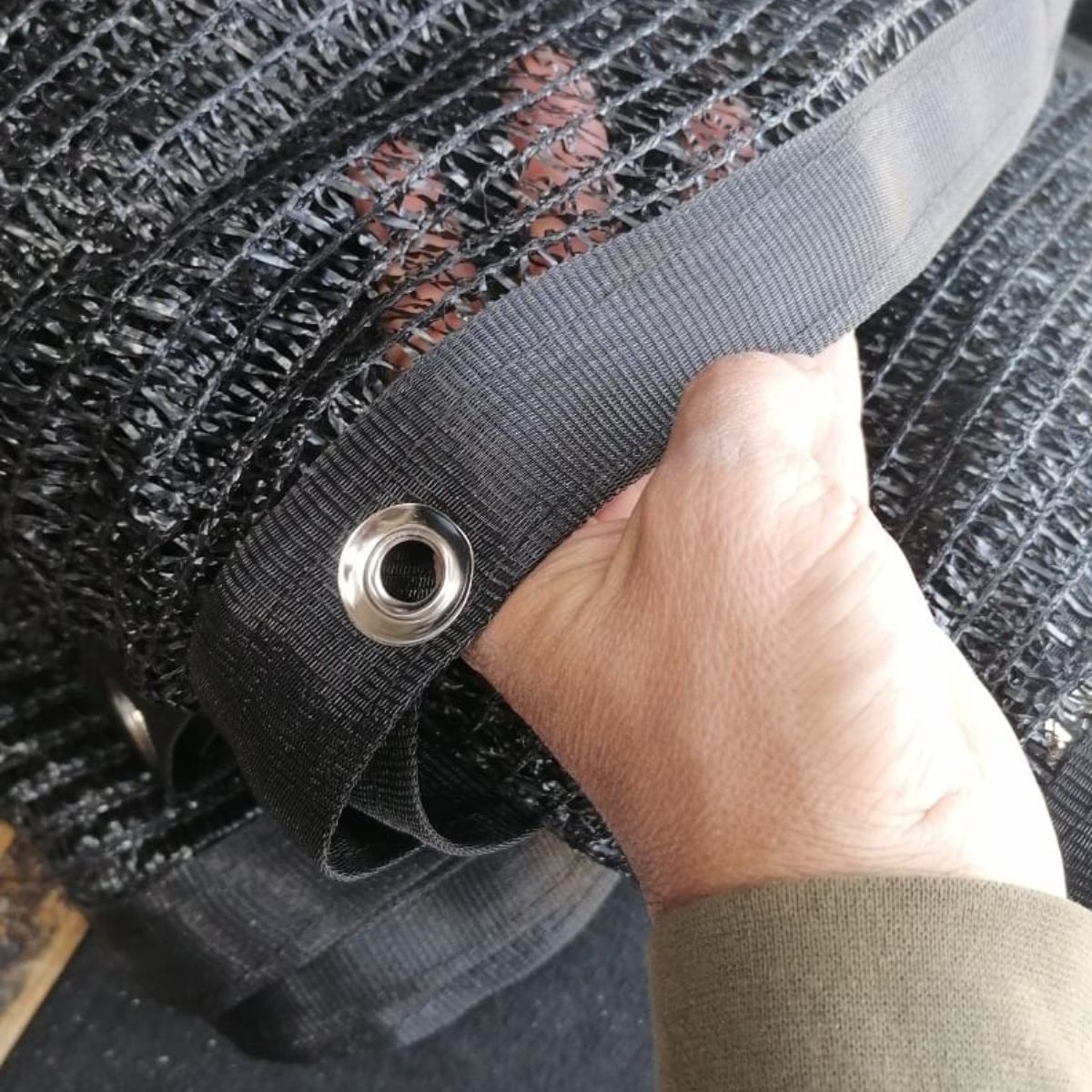 A person is holding a piece of black fabric with a hole in the middle.