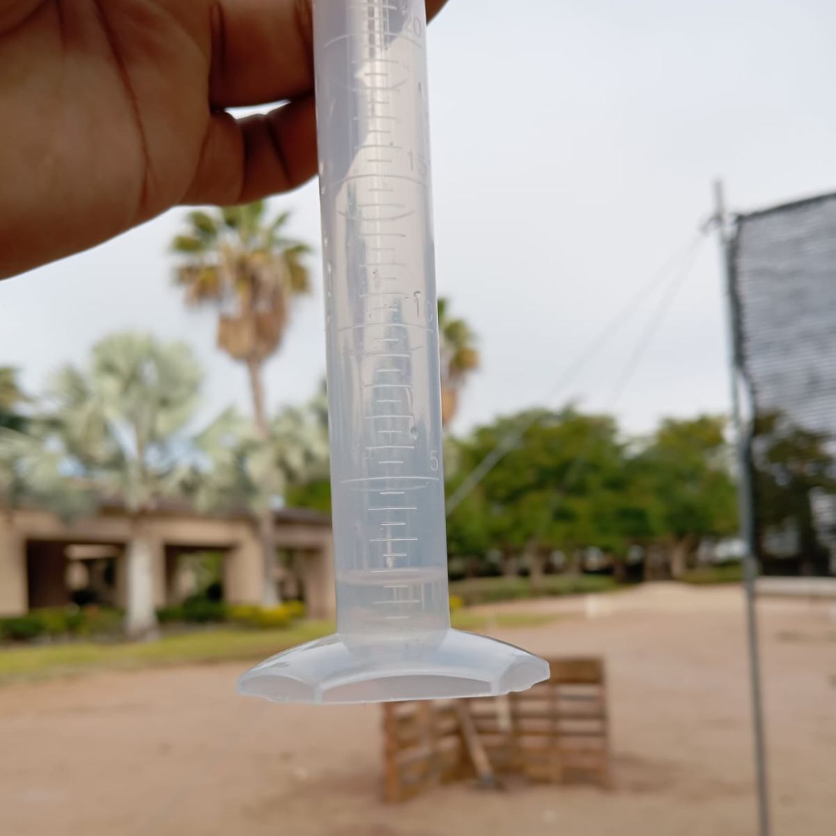 A person is holding a clear plastic measuring cup in their hand.