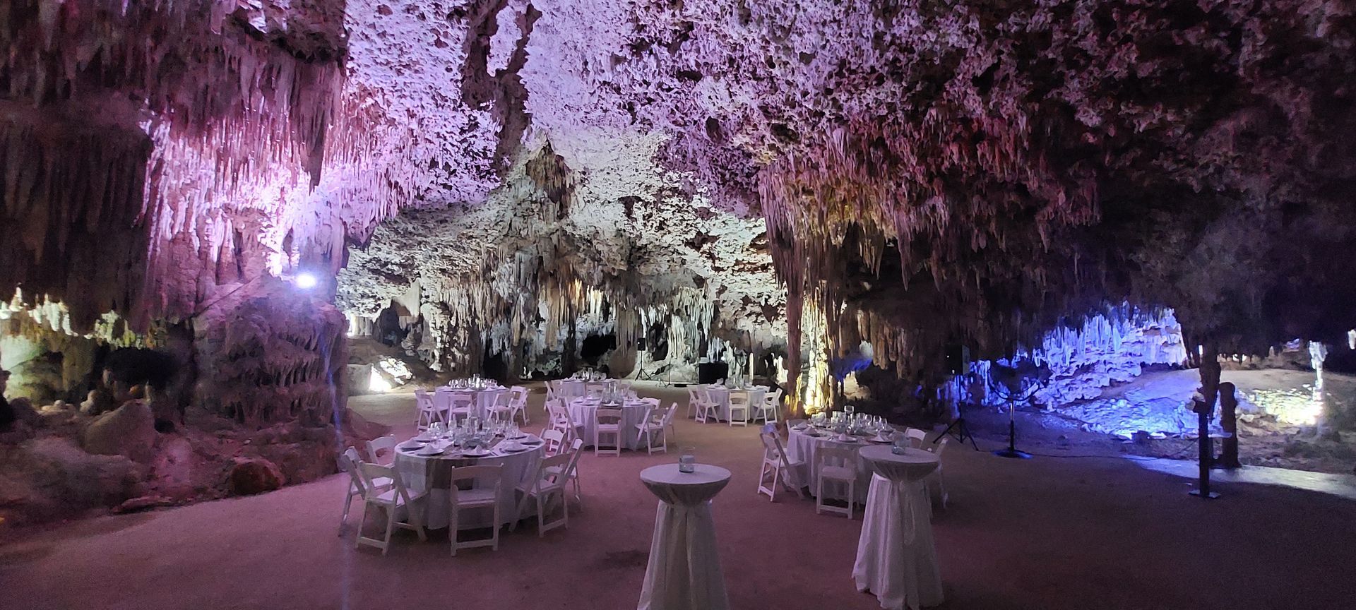 A large cave filled with tables and chairs and purple lights.