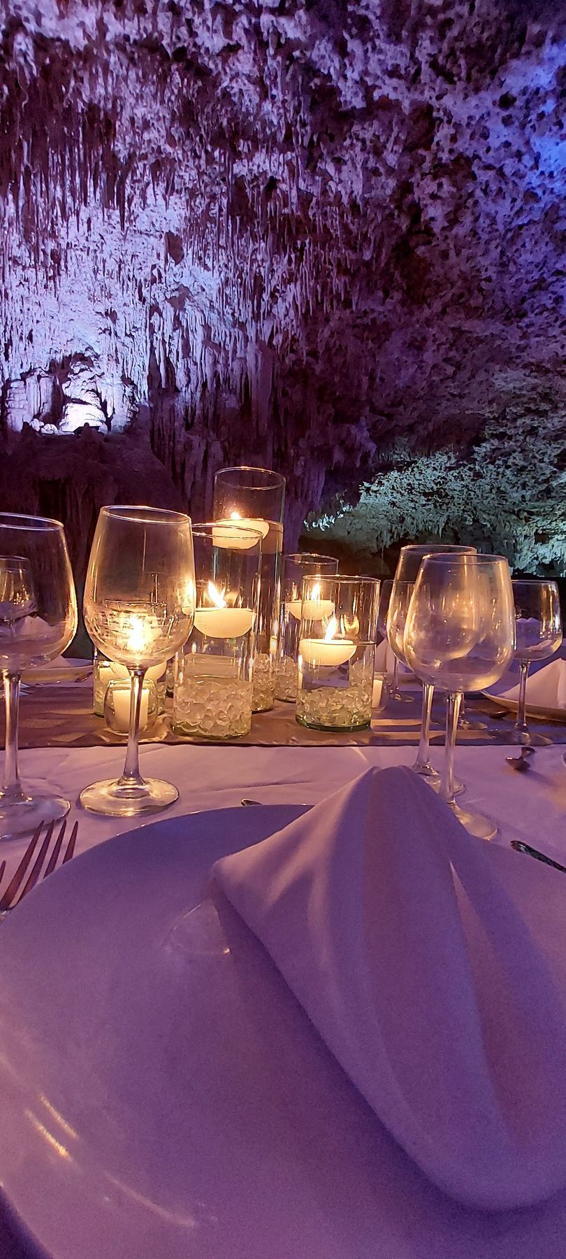 A table set with plates , wine glasses , and candles.