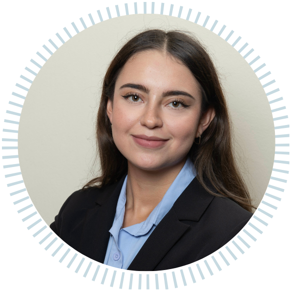 A woman in a blue jacket and necklace smiles for the camera