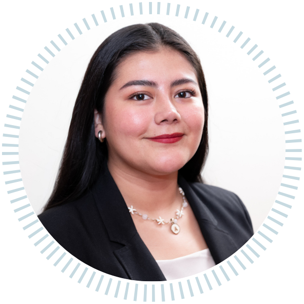 A woman in a blue jacket and necklace smiles for the camera
