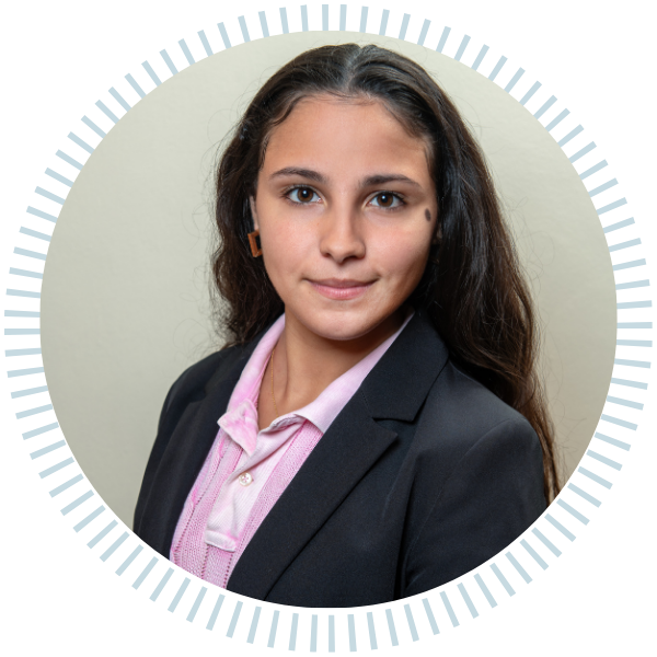 A woman in a blue jacket and necklace smiles for the camera