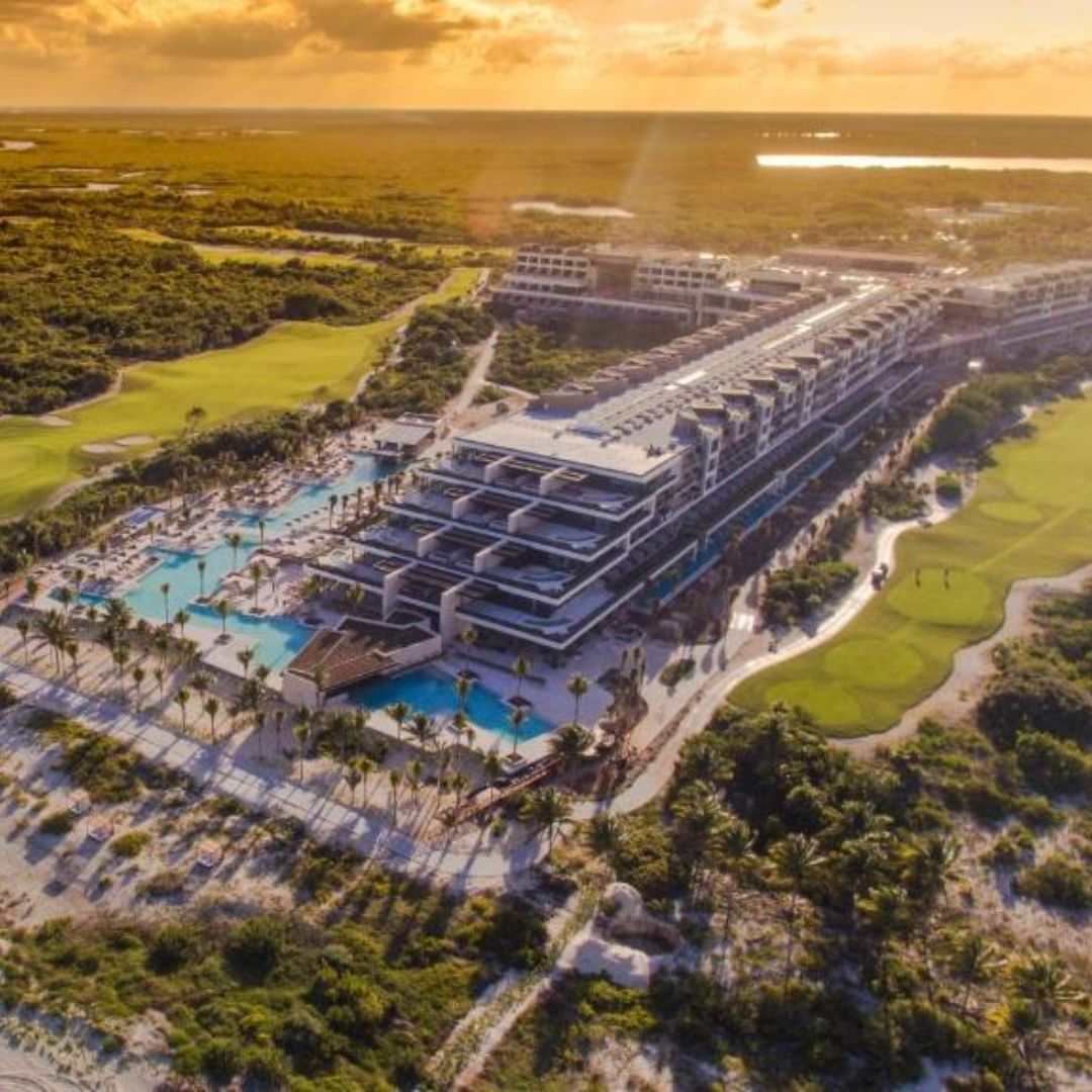 An aerial view of a large hotel surrounded by trees and a golf course.