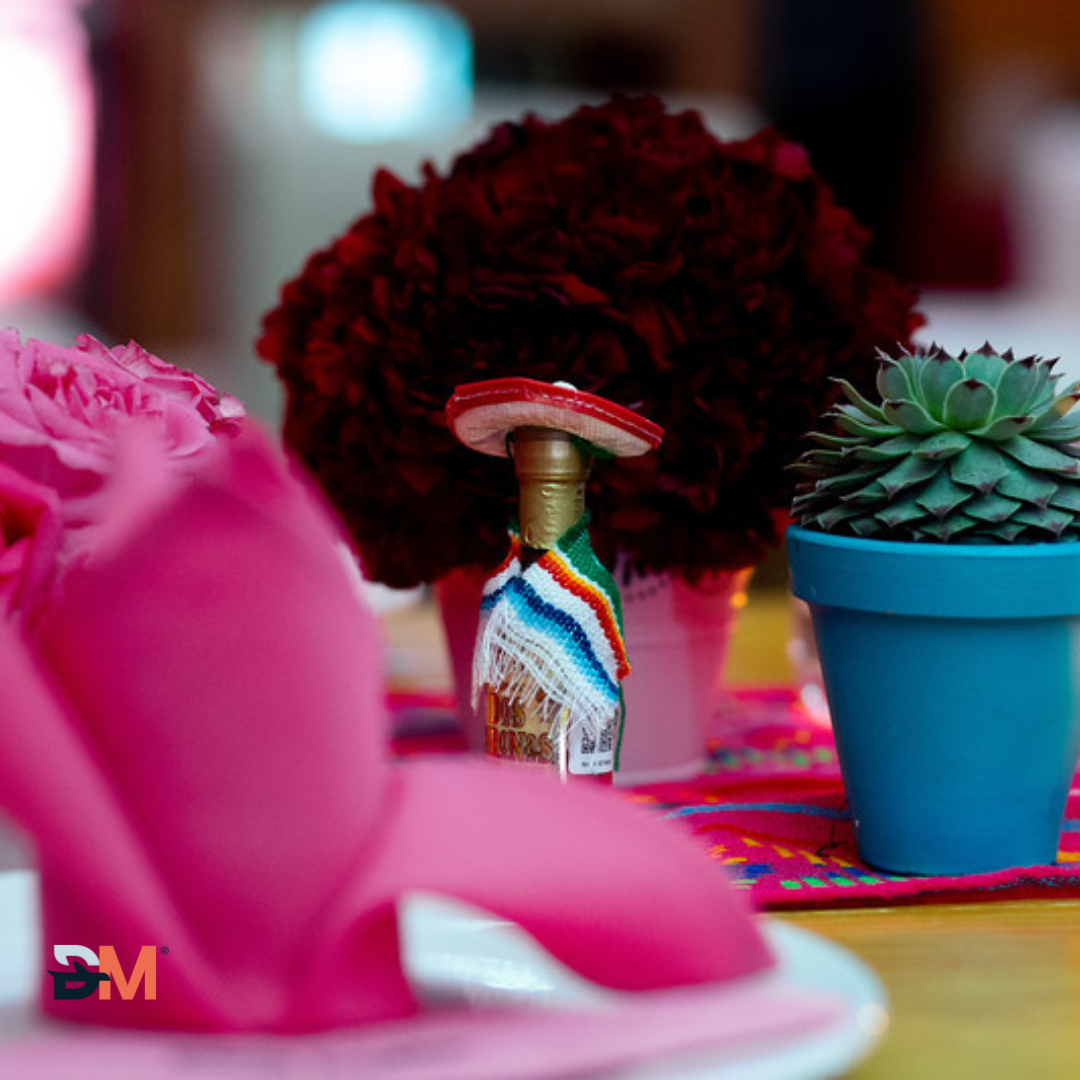 A bottle of tequila sits on a table next to a potted plant