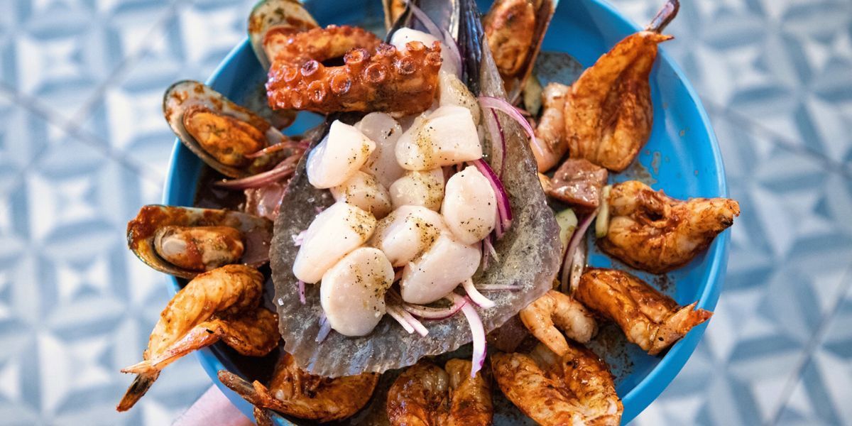 A blue bowl overflowing with seafood ceviche, including octopus, scallops, and mussels.