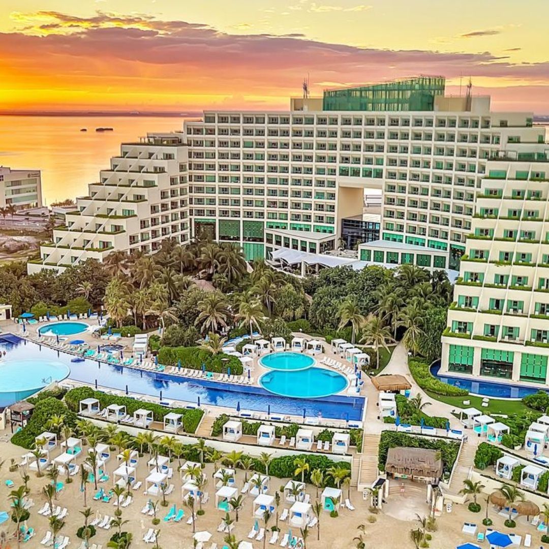 An aerial view of a large hotel with a swimming pool and a beach.