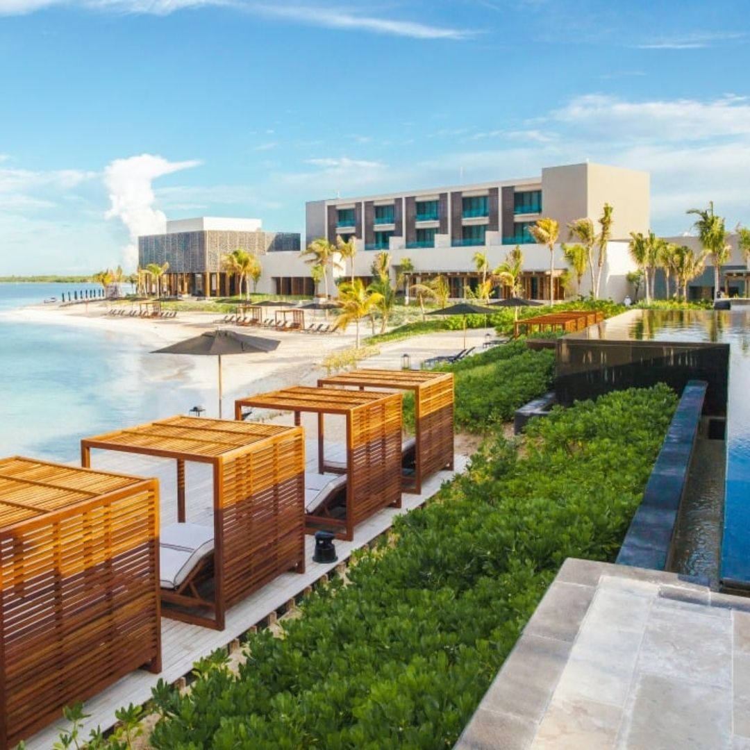 A row of wicker beds are lined up in front of a hotel