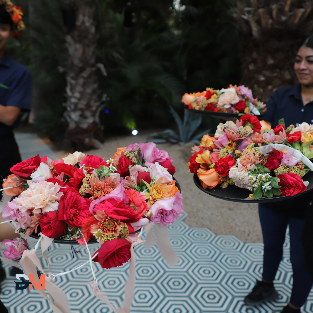A woman is holding two trays of flowers in her hands