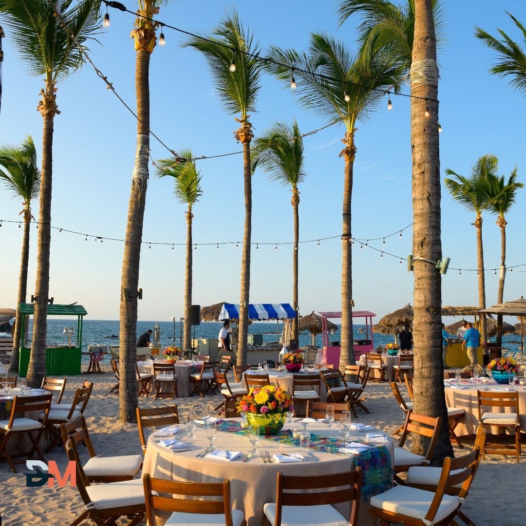 Tables and chairs set up on the beach with palm trees in the background