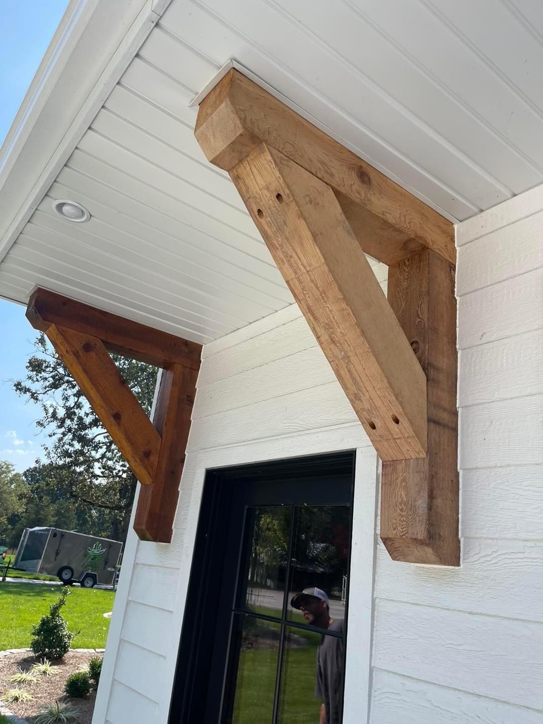 A wooden bracket is attached to the side of a white house.
