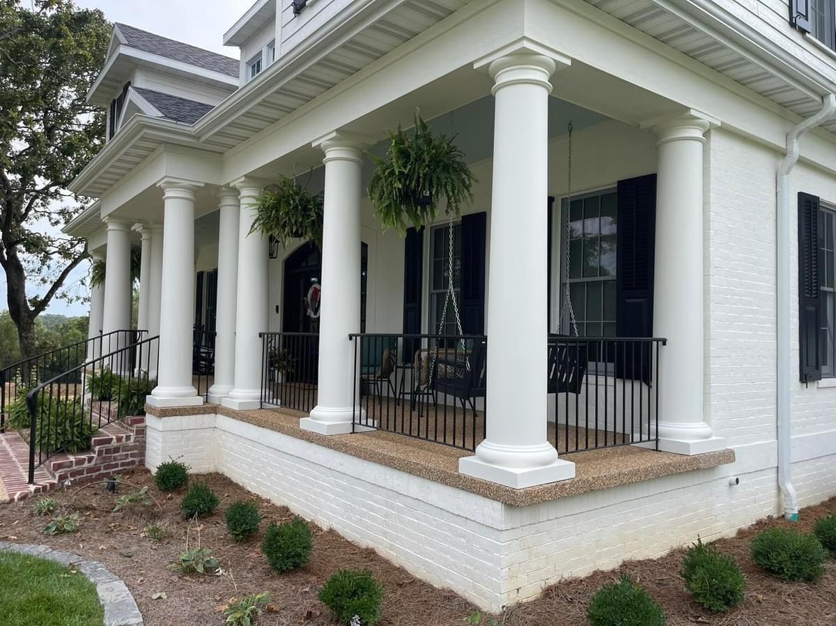 A large white house with a porch and black shutters.