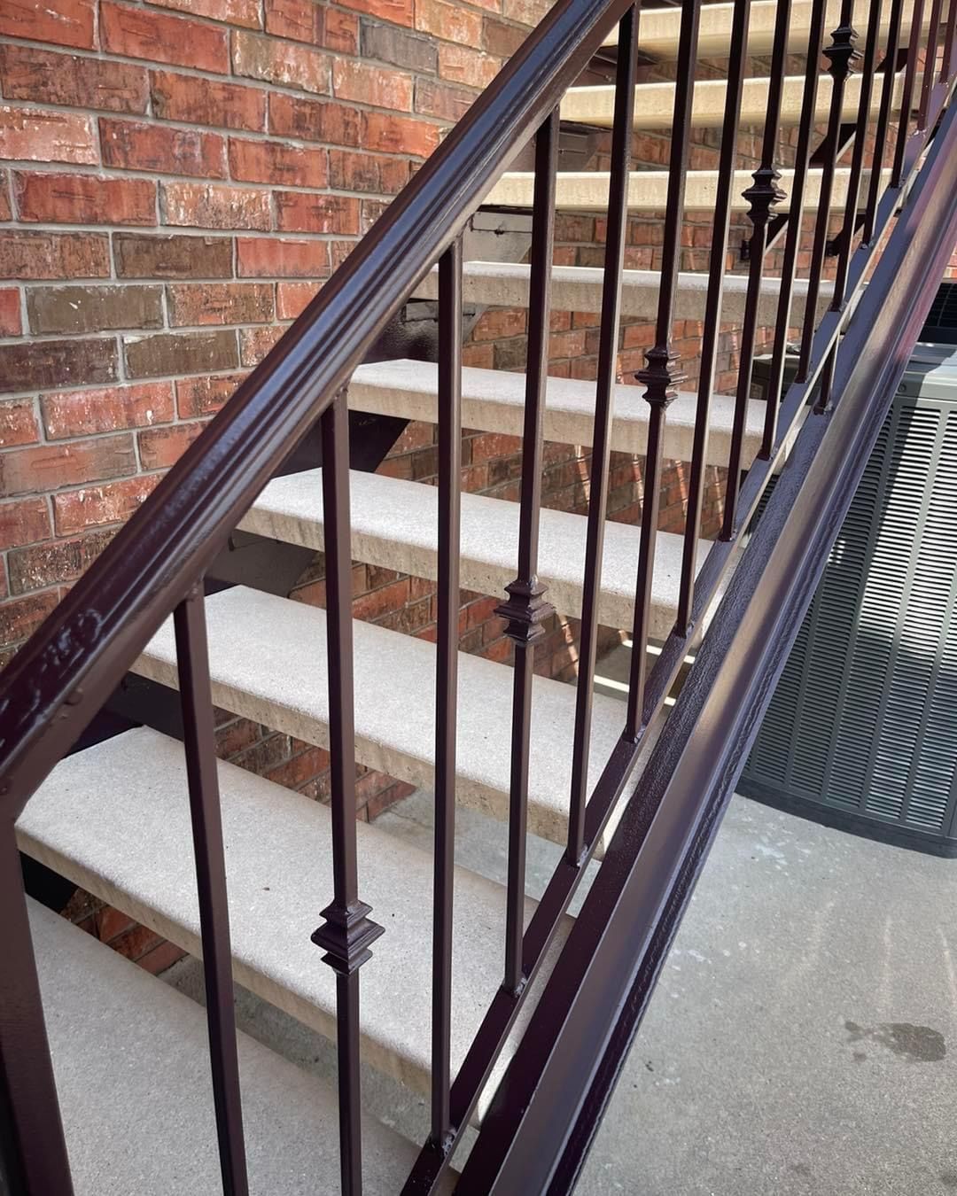 A set of stairs with a metal railing and a brick wall behind them