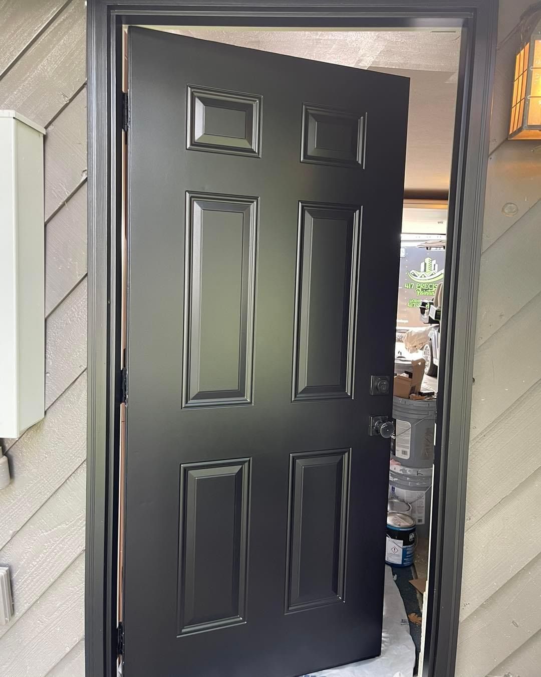A black door is open on the side of a house.