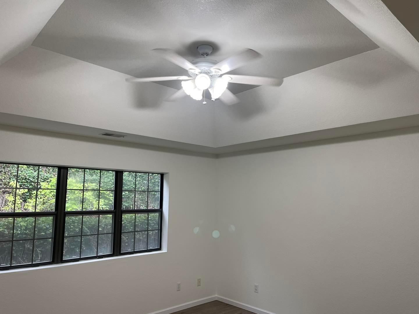 An empty room with a ceiling fan and a window