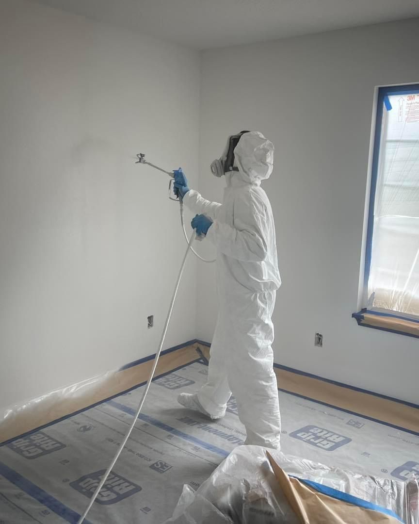A person in a white suit is spraying paint on a wall