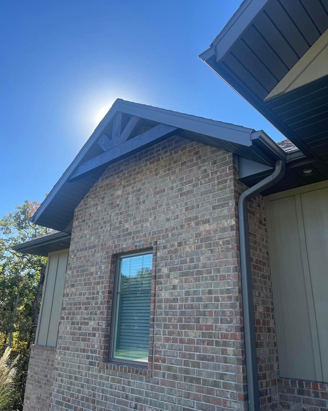 A brick house with a window and a black roof.