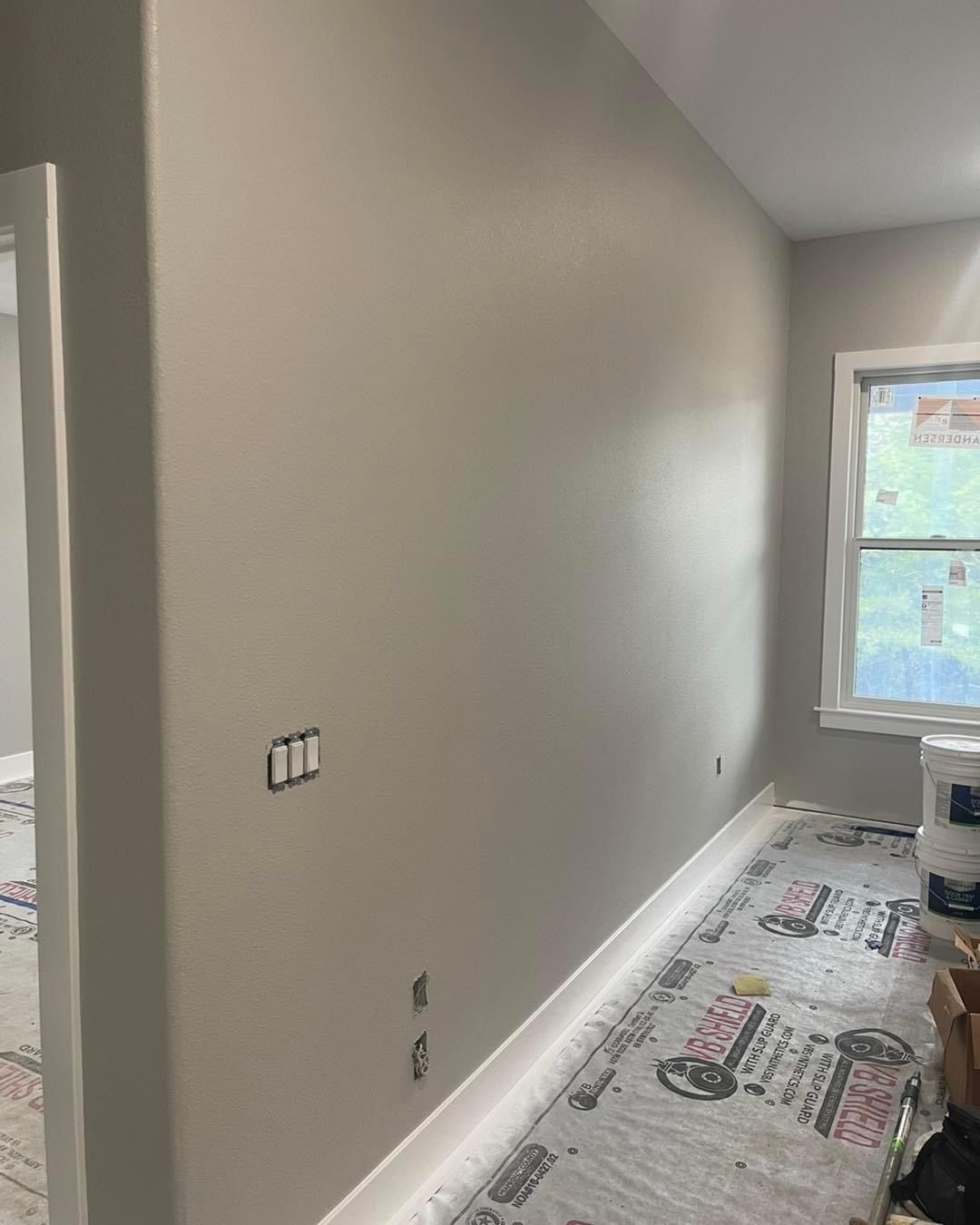 A room with a large wall and a window being painted.
