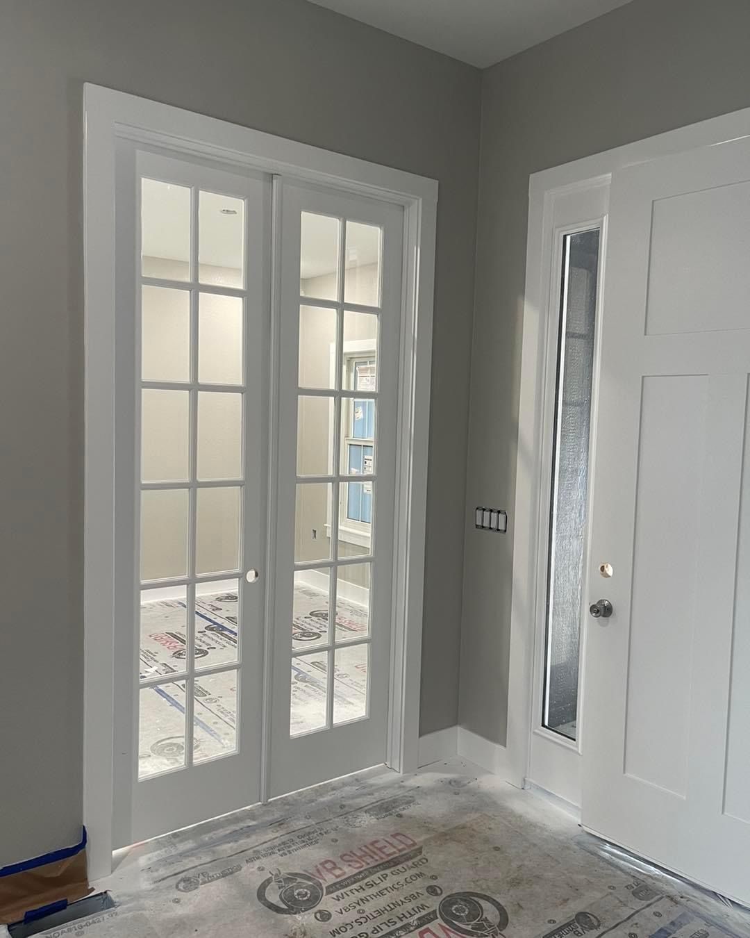 A room with french doors and a rug on the floor.