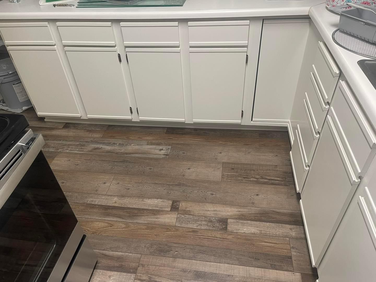 A kitchen with white cabinets and a wooden floor.