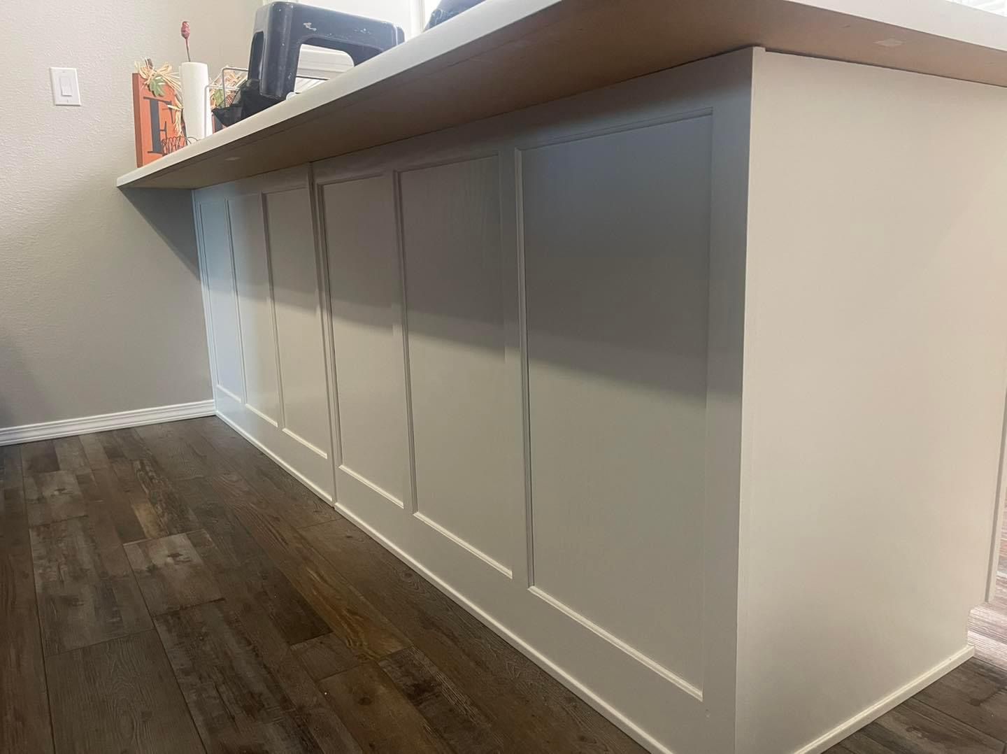 A kitchen island with white cabinets and hardwood floors.