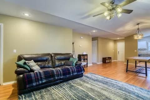 A living room with a couch , rug , table and ceiling fan.