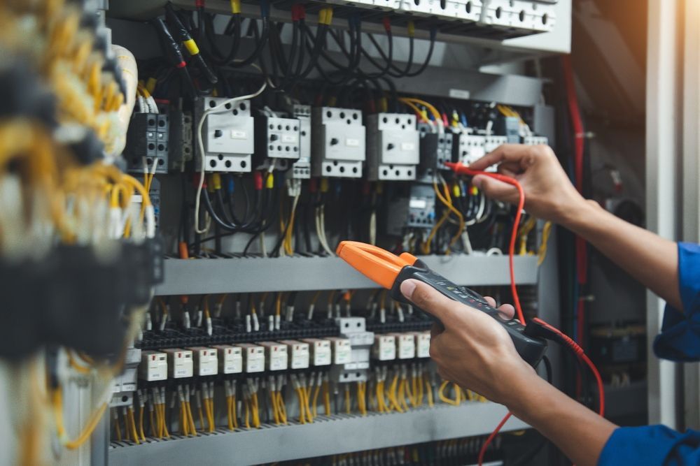 An Electrician Is Working on An Electrical Panel with A Multimeter — B2B Electrical and Solar In Caloundra, QLD