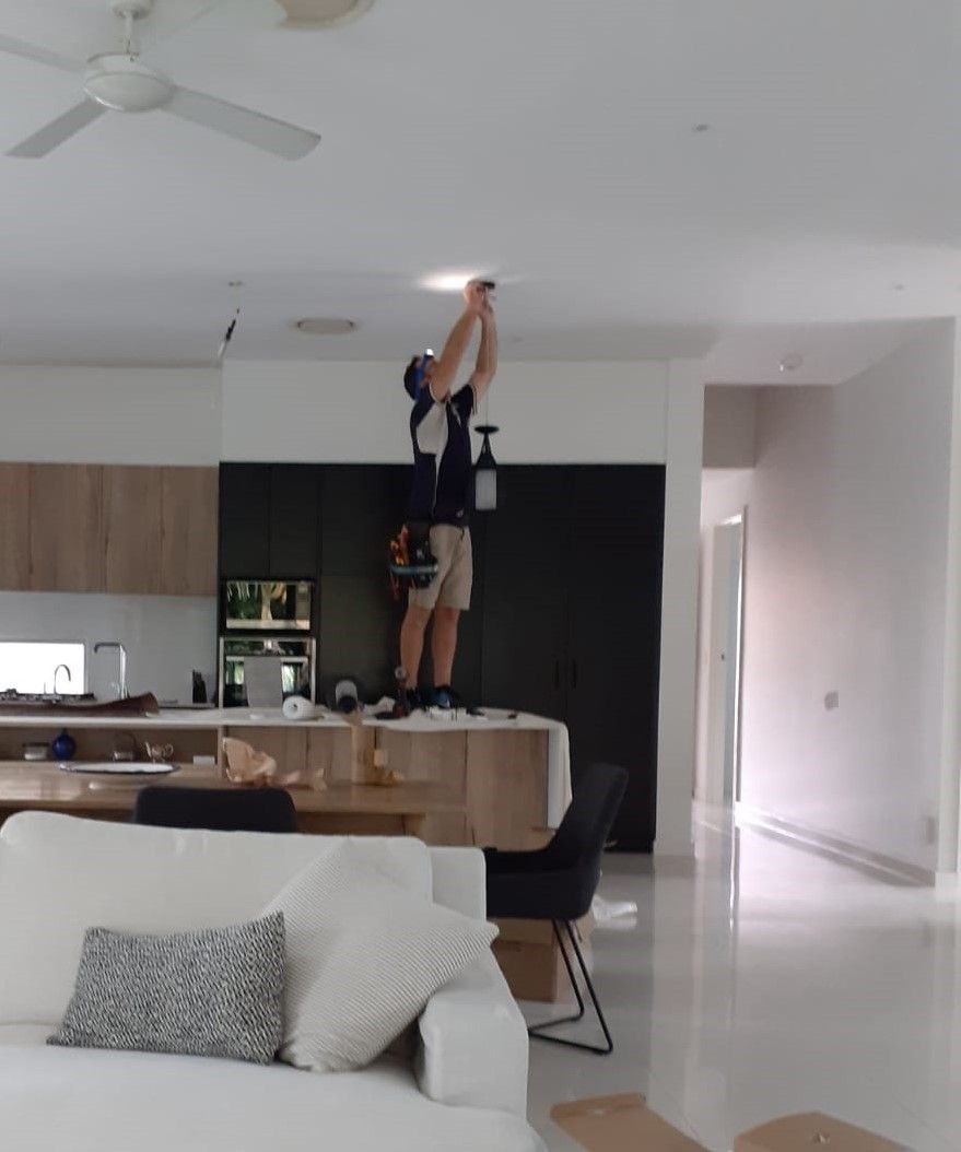 A man is working on a light fixture in a living room — B2B Electrical and Solar In Currimundi, QLD