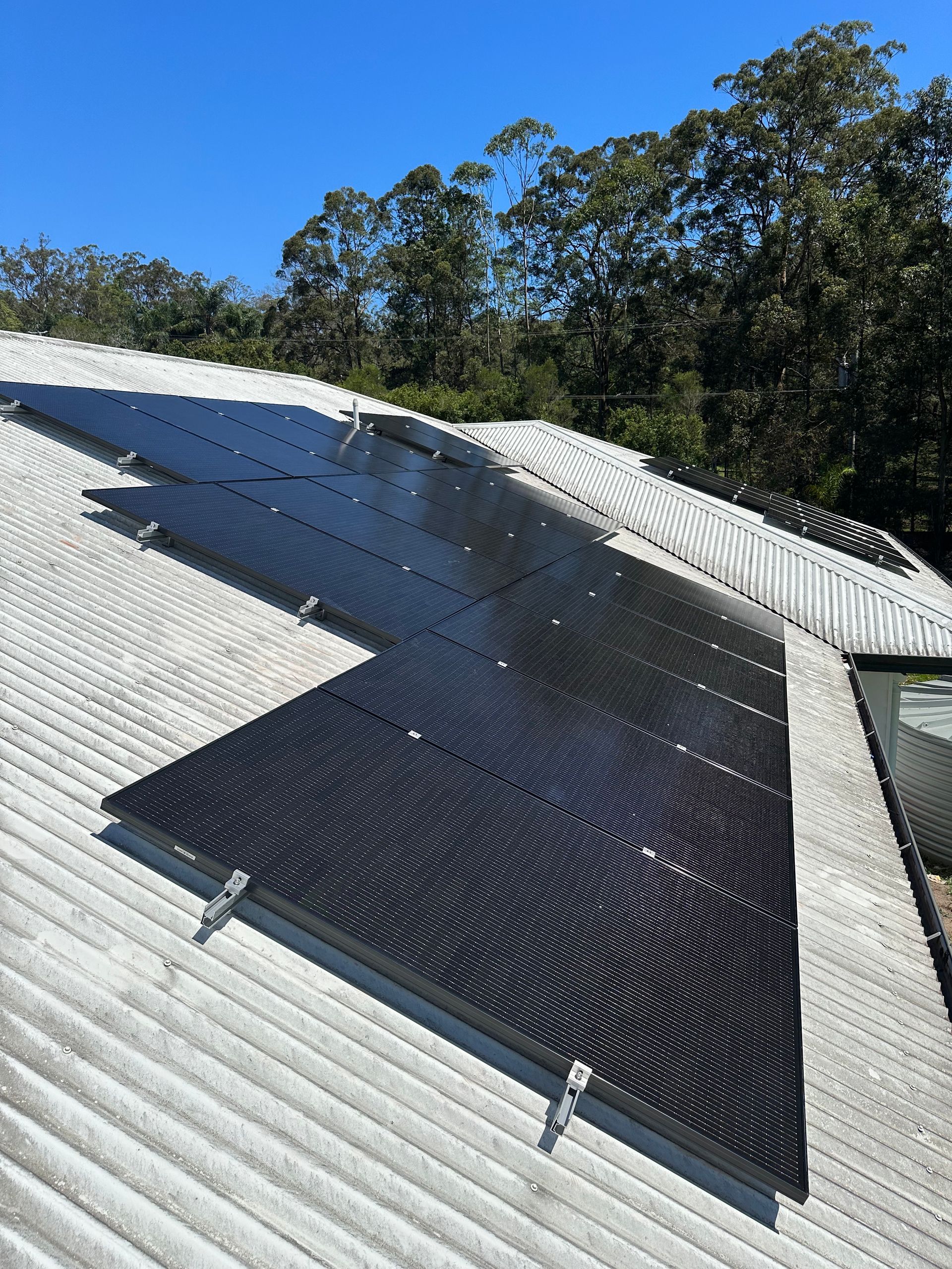 A Man is Holding a Thermometer in Front of a Solar Panel — B2B Electrical and Solar In Currimundi, QLD A roof with a lot of solar panels on it — B2B Electrical and Solar In Currimundi, QLD