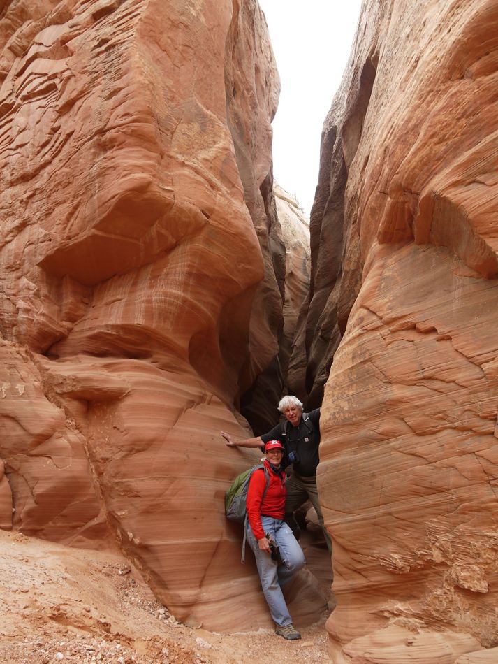 Two people are standing in a canyon between two rocks