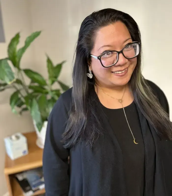 A woman wearing glasses and a black shirt smiles for the camera