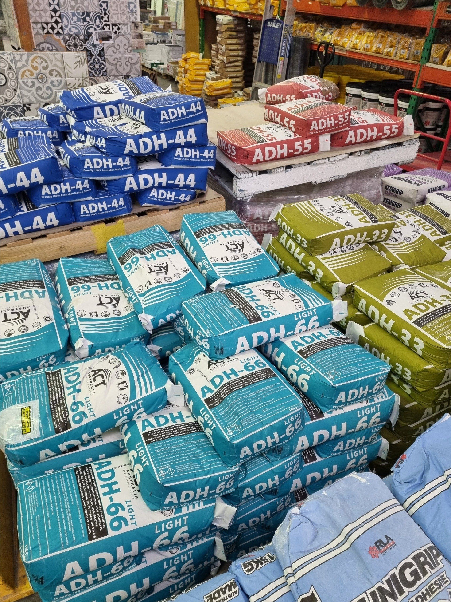 A bunch of bags of cement are stacked on top of each other in a store.